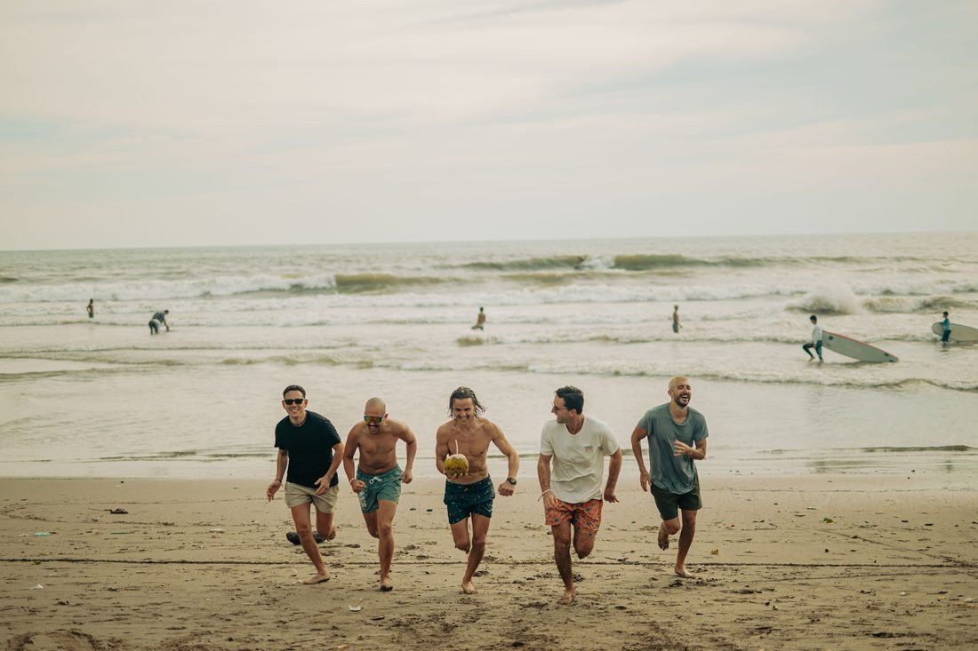 A group walking out of the surf onto the sand on Bali's west coast